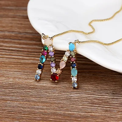 Collar con iniciales y piedras preciosas doradas de 18 quilates